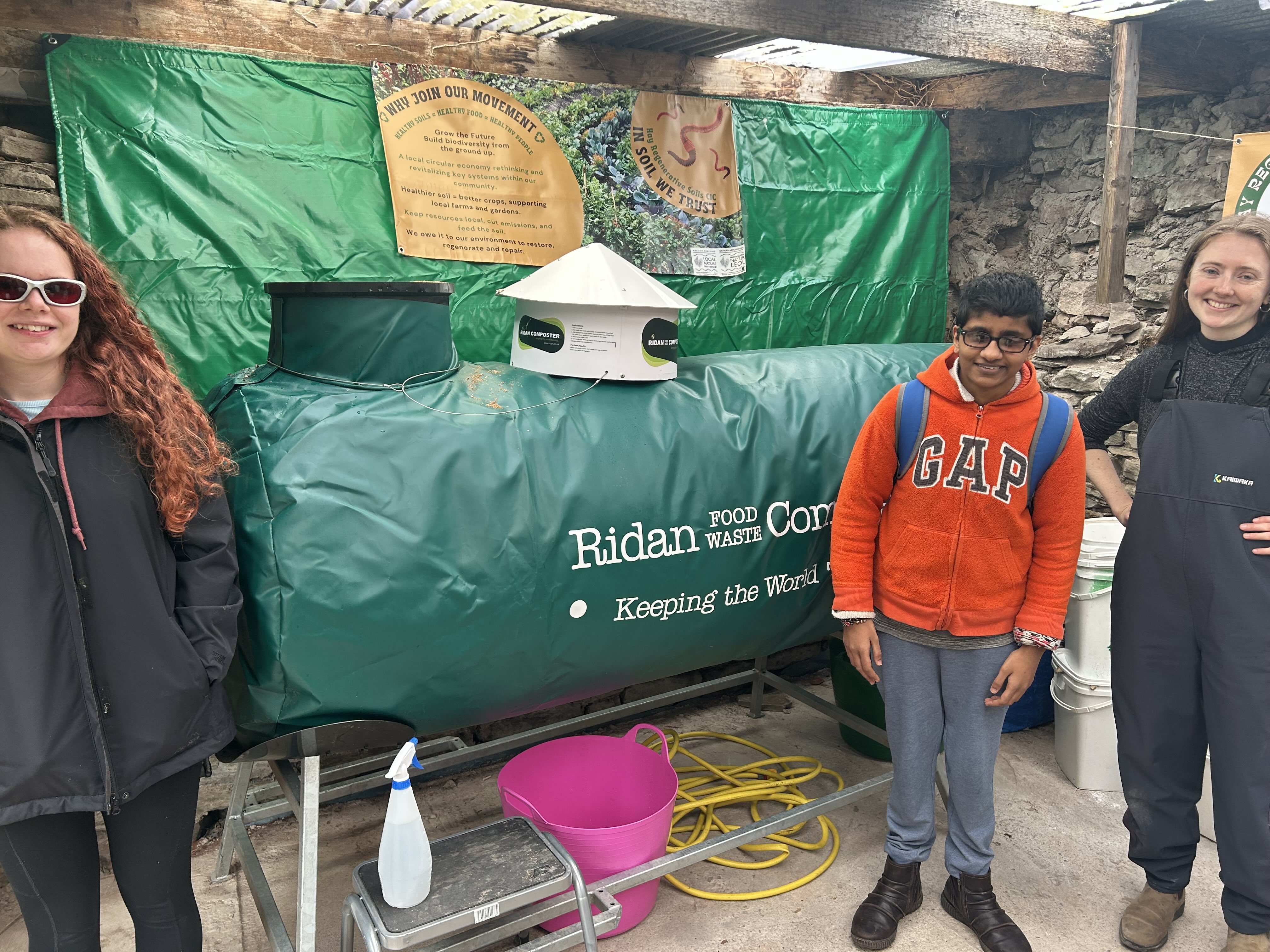 3 people standing in front of a giant composter