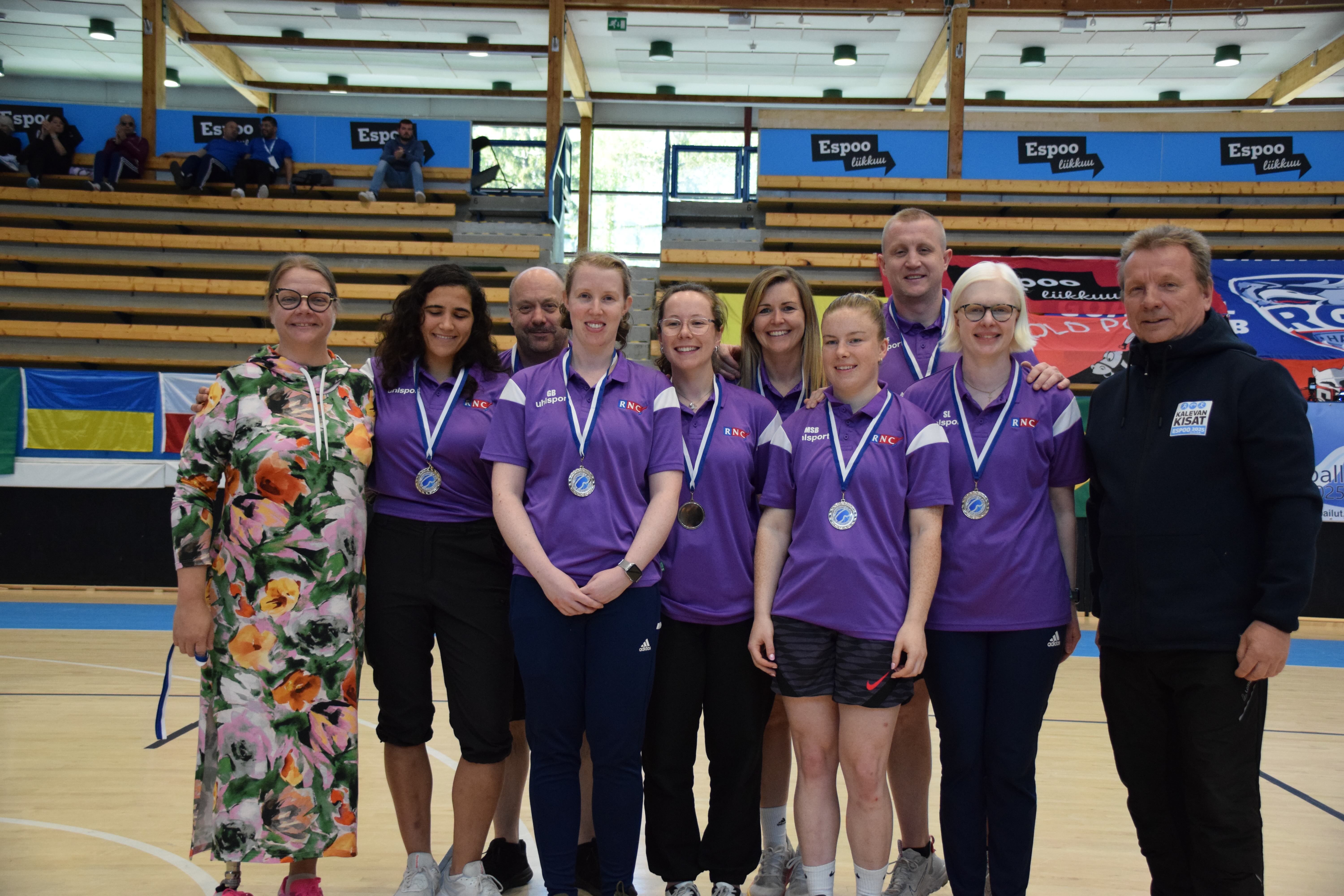 the team and coaches line up with officials proudly displaying their medals
