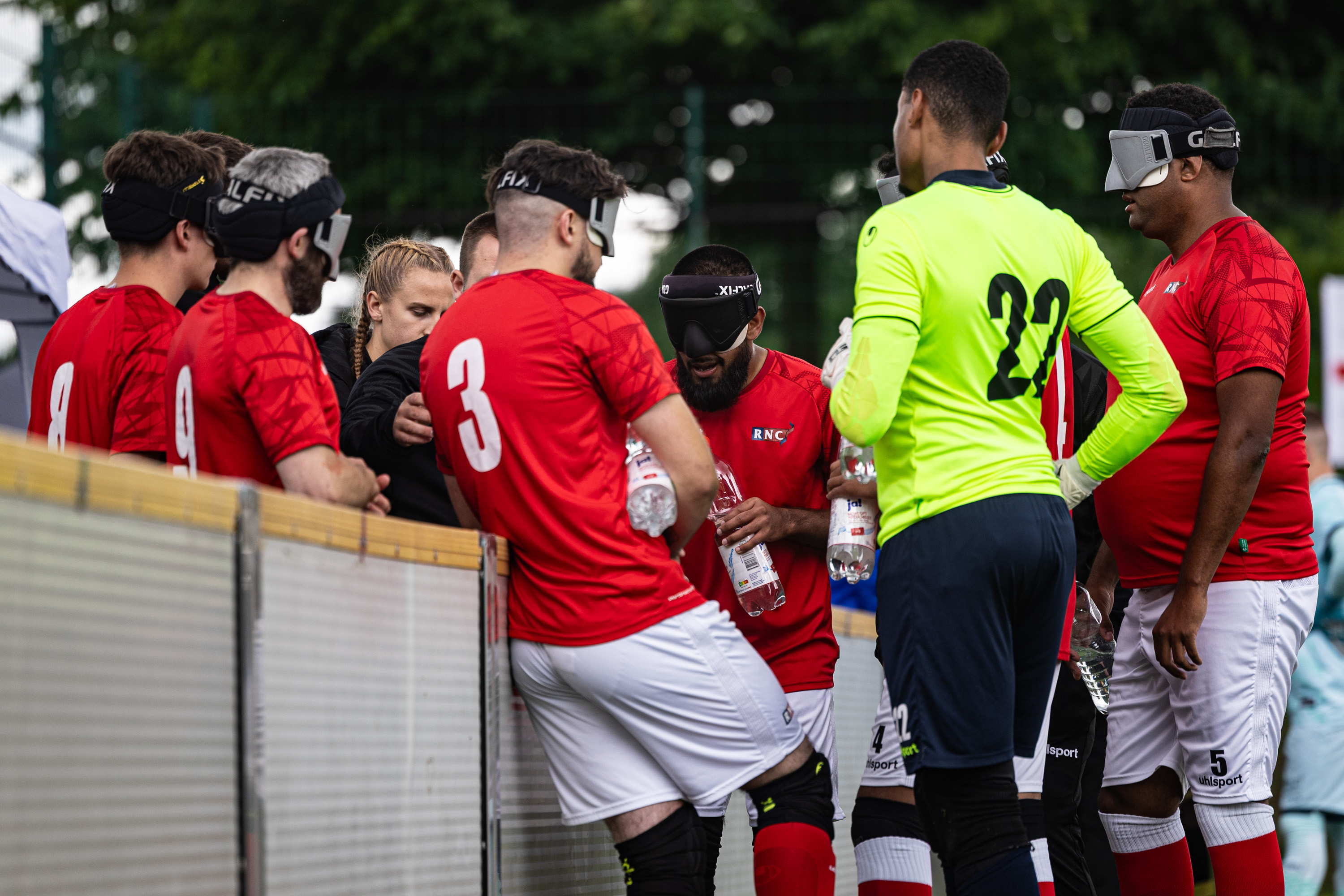 The RNC huddle in a team talk - they wear a red jersey and white shorts 