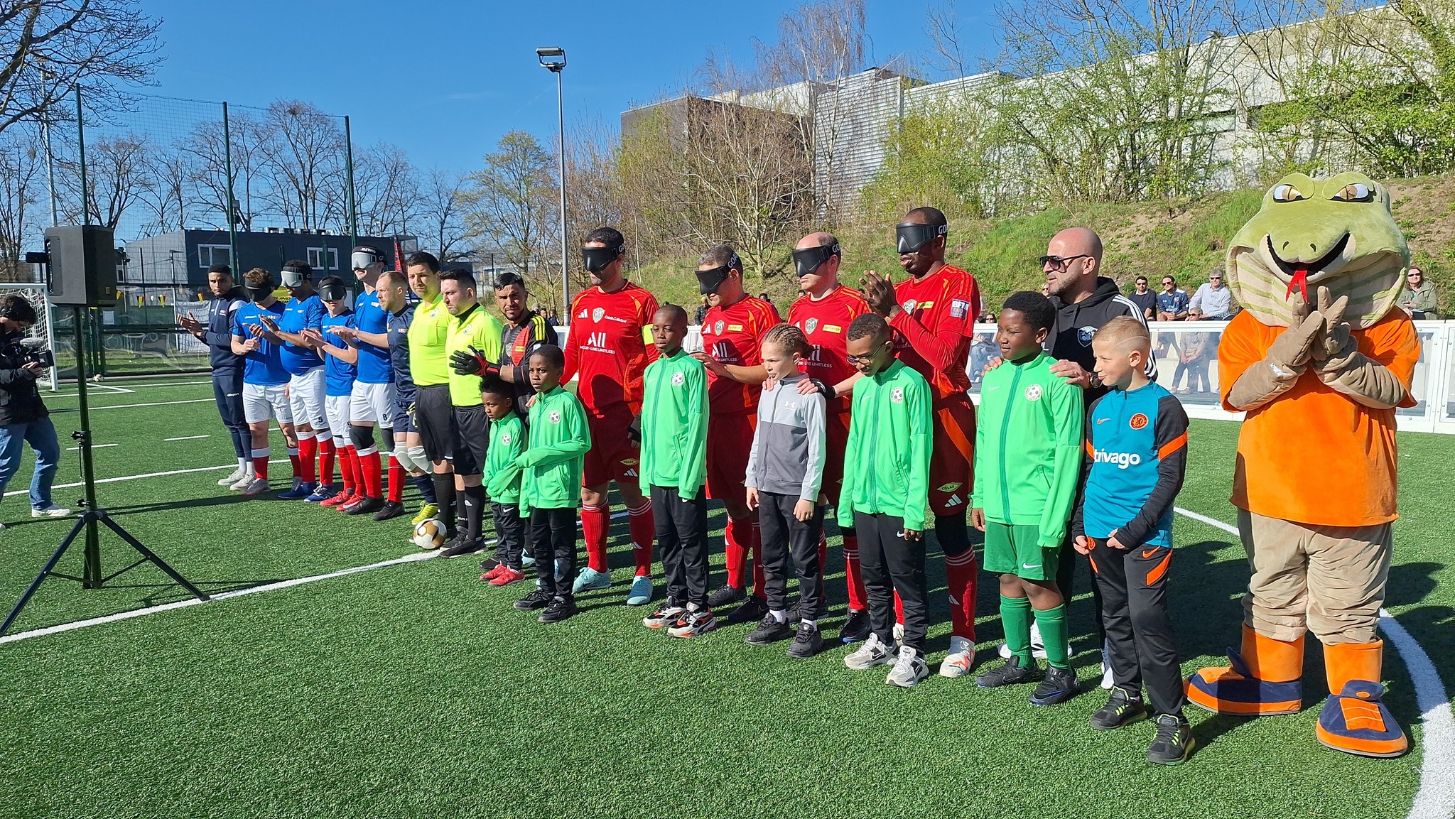 teams RNC and Bondy line up before the match there are young mascots standing in front of the body team and their club mascot a giant furry snake os to the right of the picture