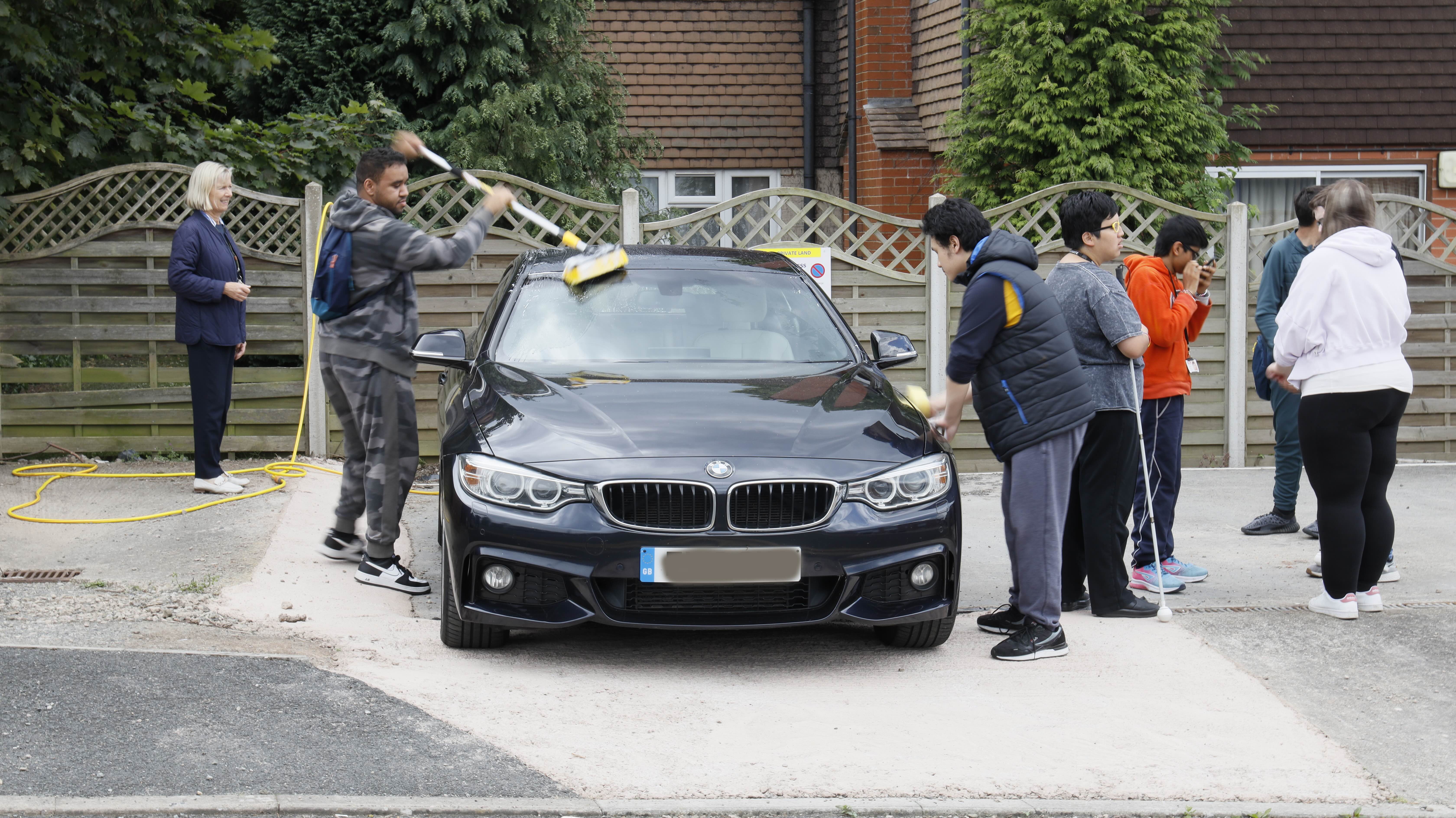 A group of students around a car washing it