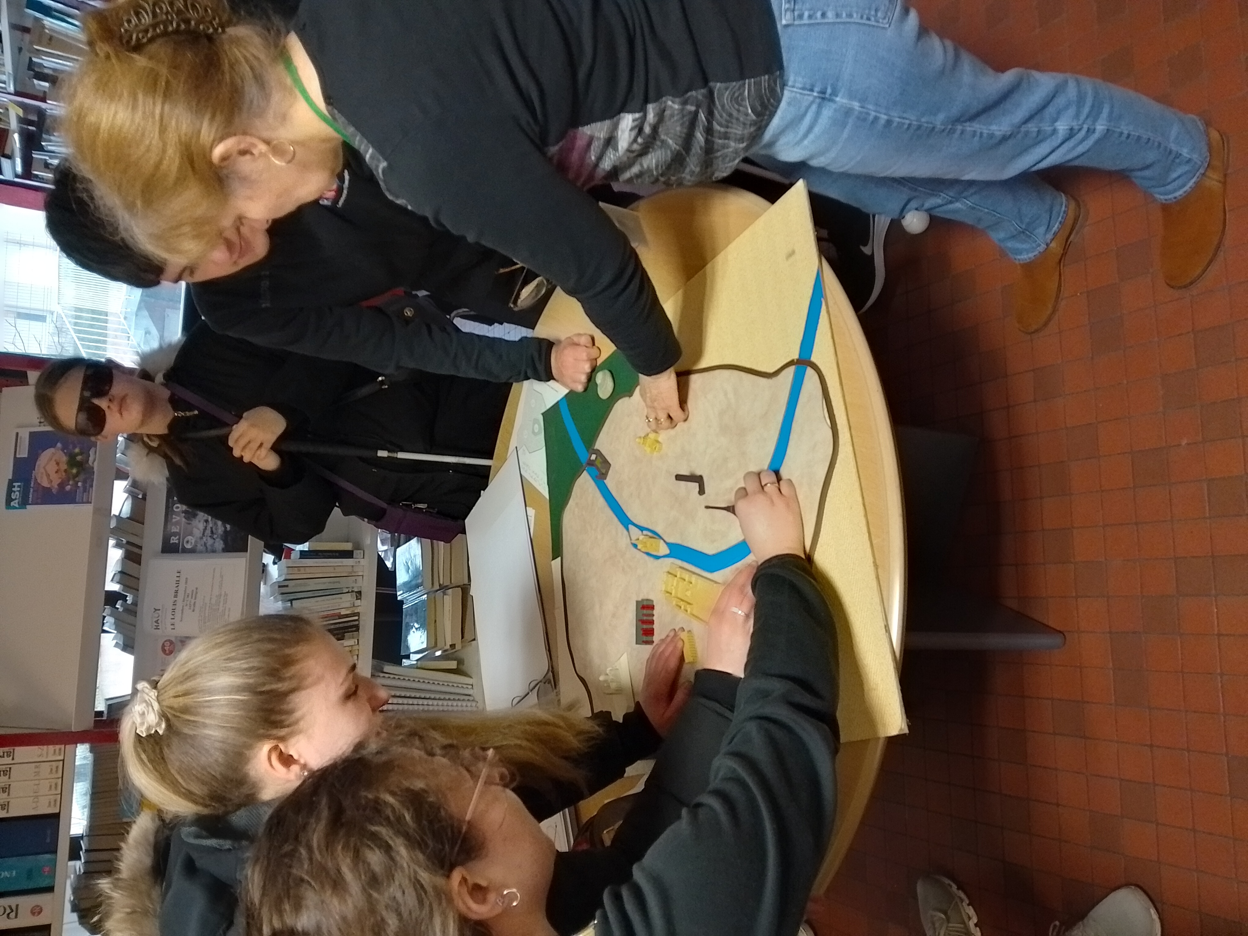 the group stand around a table which has the tactile map of Paris on it