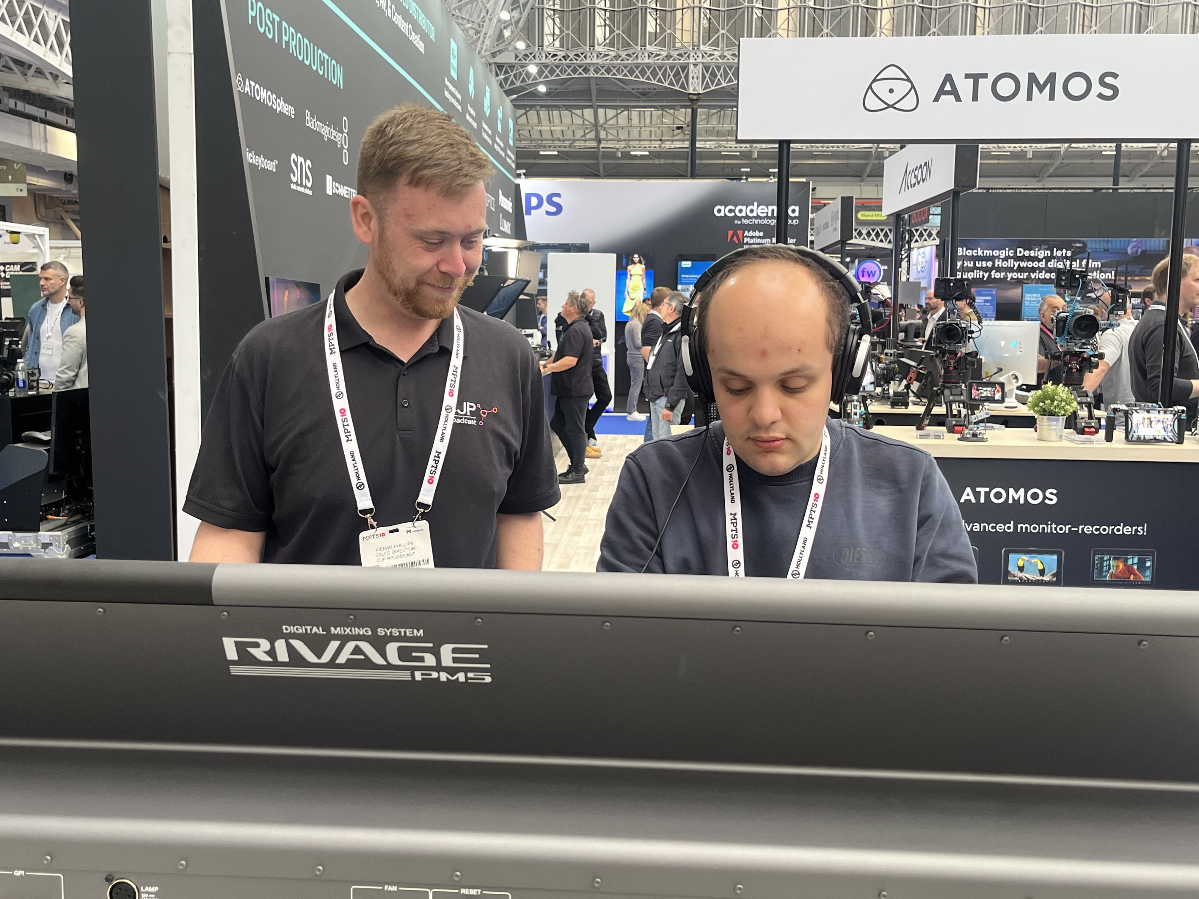 Davide wearing headphones and trying out a mixing desk - Kieran stands next to him watching on