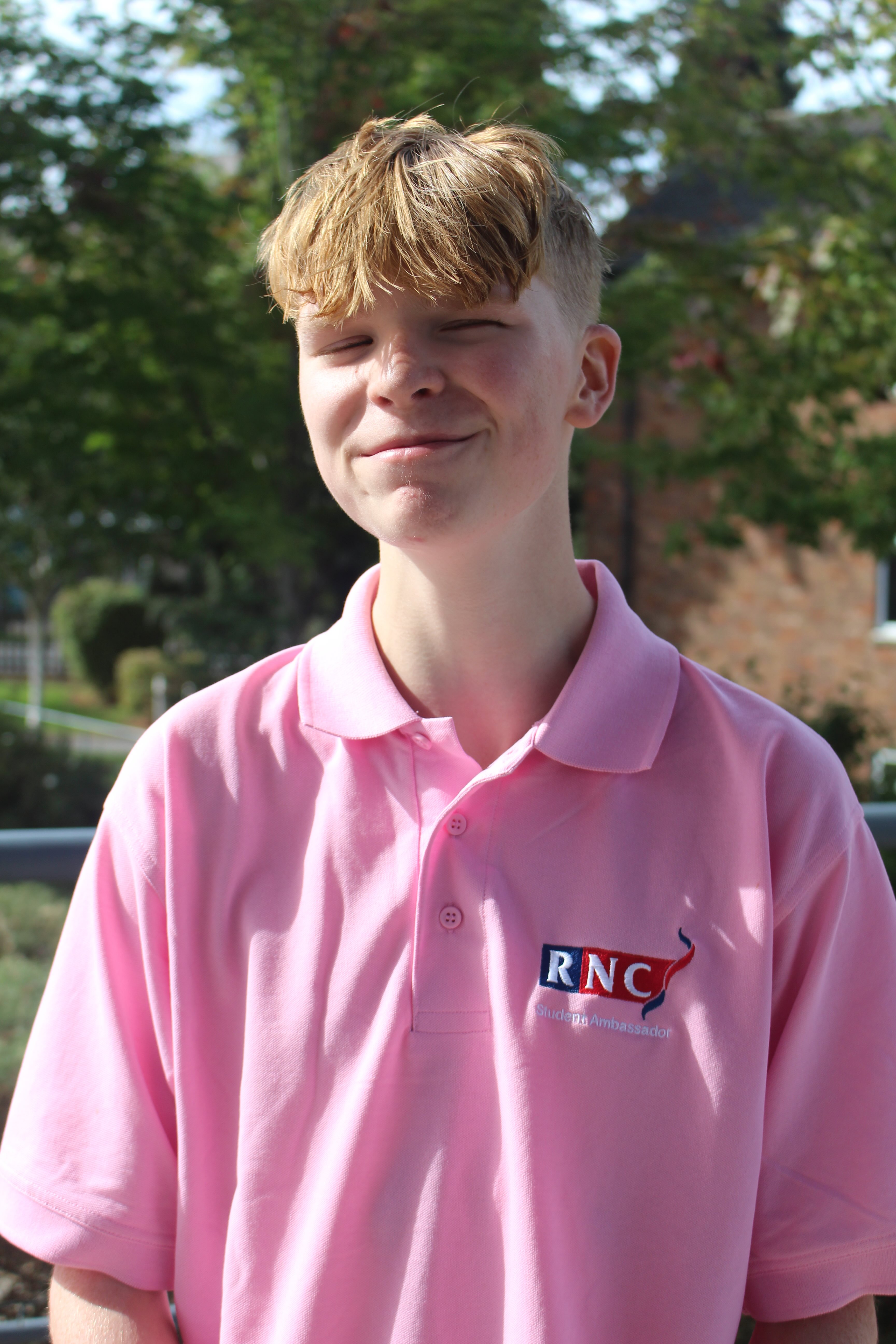 a head and shoulders shot of Oscar wearing his pink student ambassadors shirt