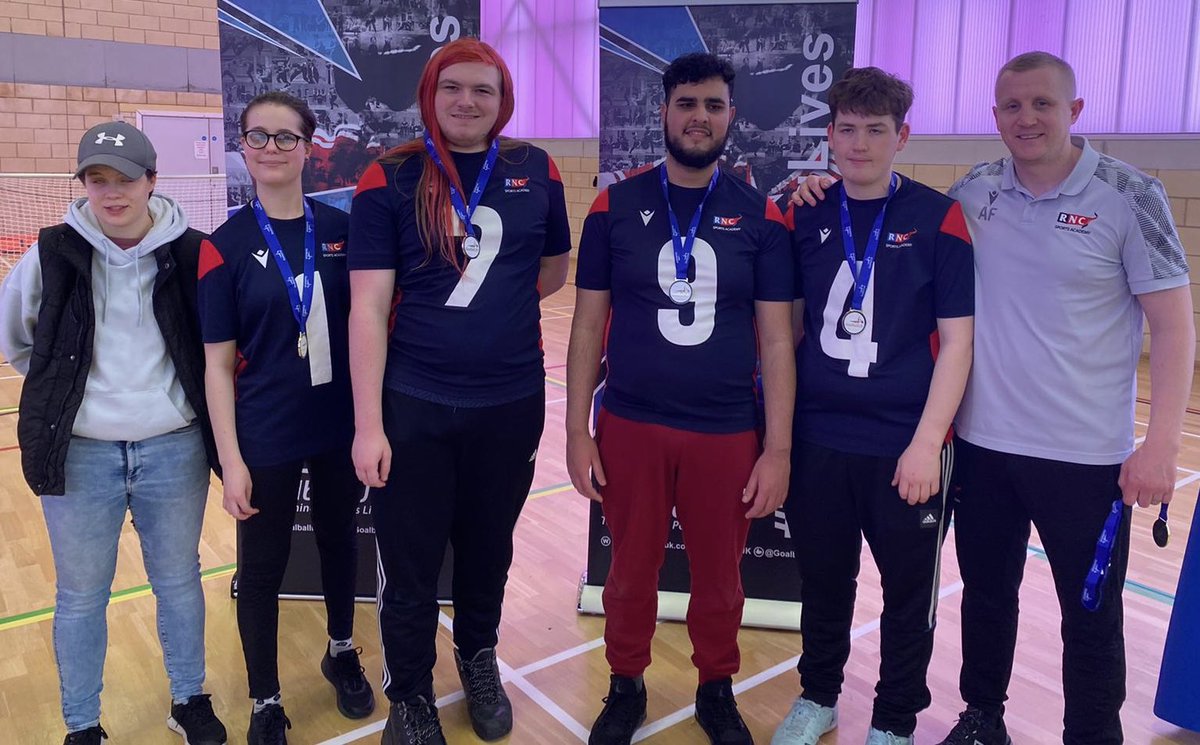  RNC students and coaches standing in front of the Goalball UK banner with their medals after being presented as the winning team.